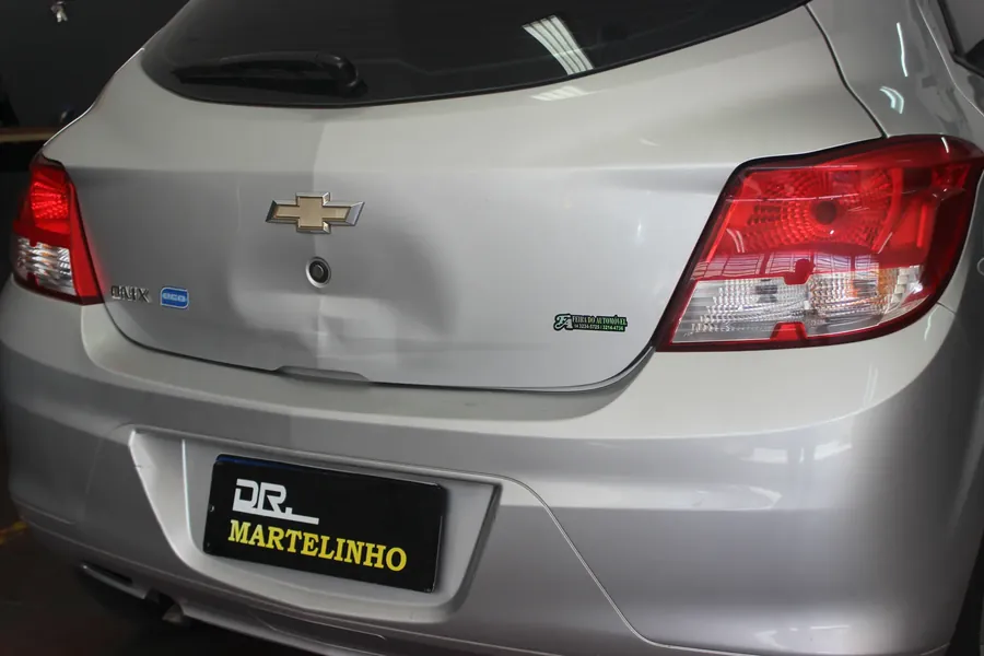 Amassado na tampa do porta-malas de Chevrolet Onix prata antes do martelinho de ouro